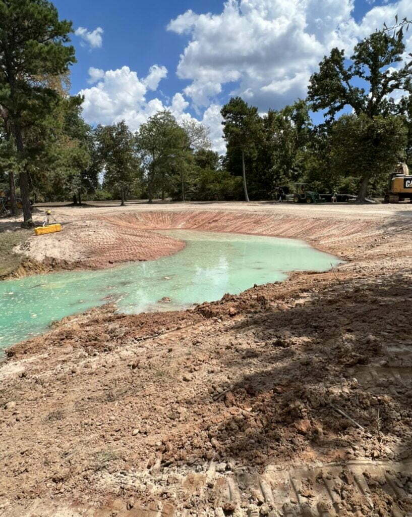 Freshly cleaned lake basin with newly graded slopes and shallow green water returning to the bottom